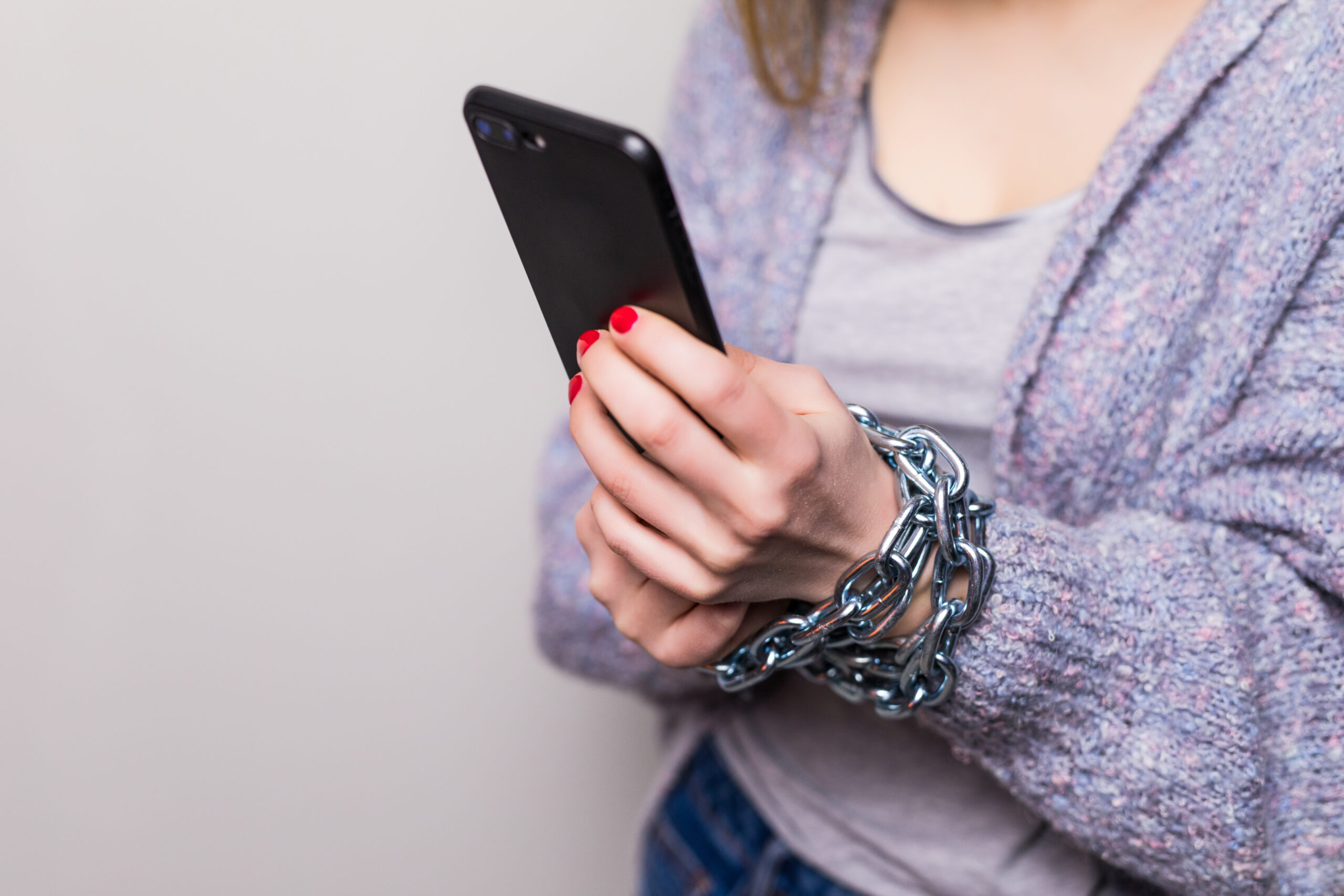 Girl with chain locked hands using a smartphone isolated on white background